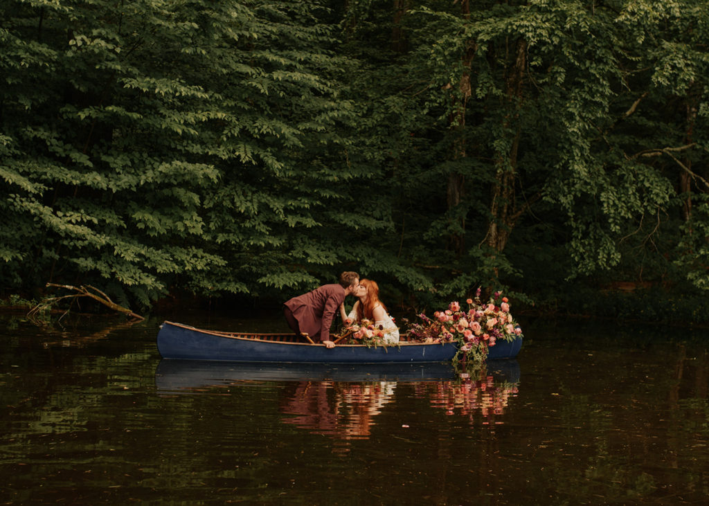 A couple canoeing along a lake in the Catskills, which is one of the best places to elope in New York!