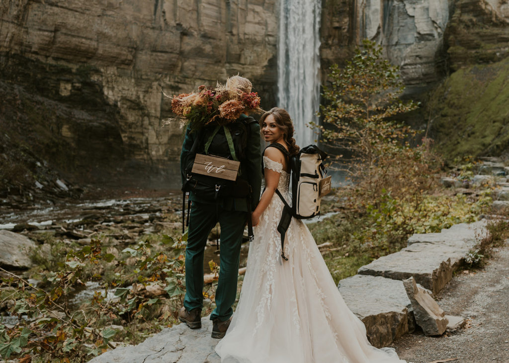 A couple standing in front of a waterfall in Ithaca, which is one of the best places to elope in New York!