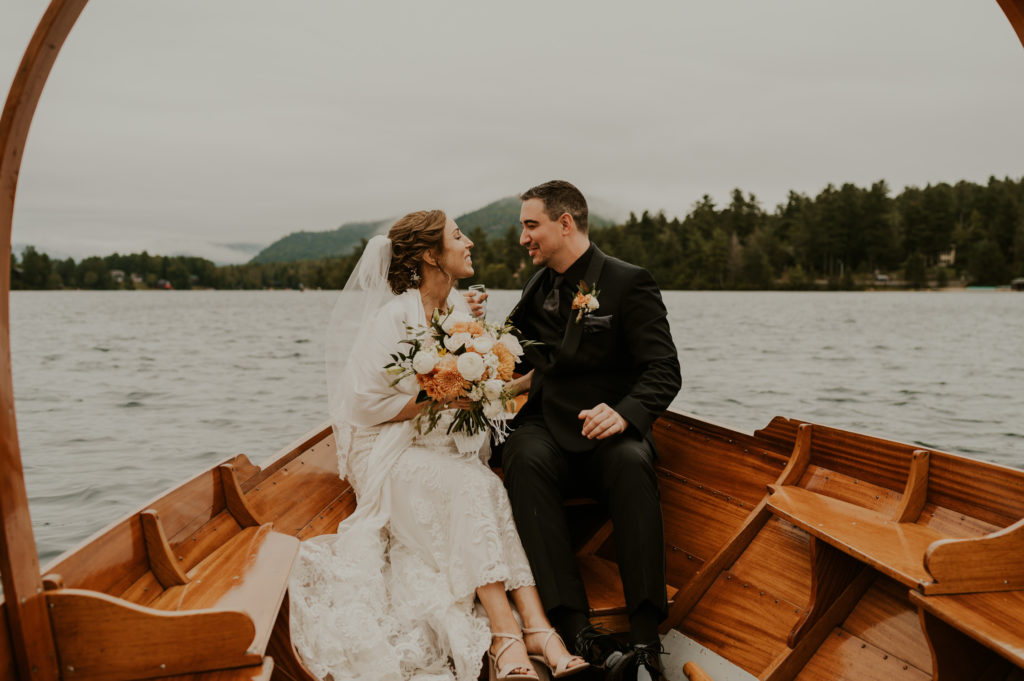 A couple sitting in a wooden canoe at their wedding venue.